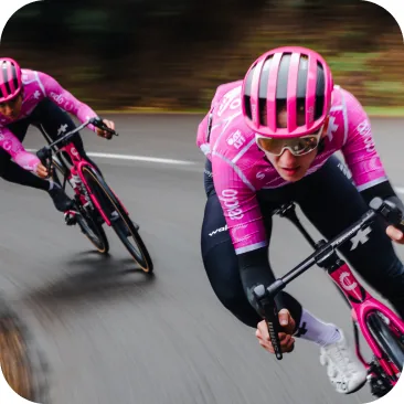 Cyclists aggressively leaning bikes into a tight corner, demonstrating the high clearance angle of the pedals